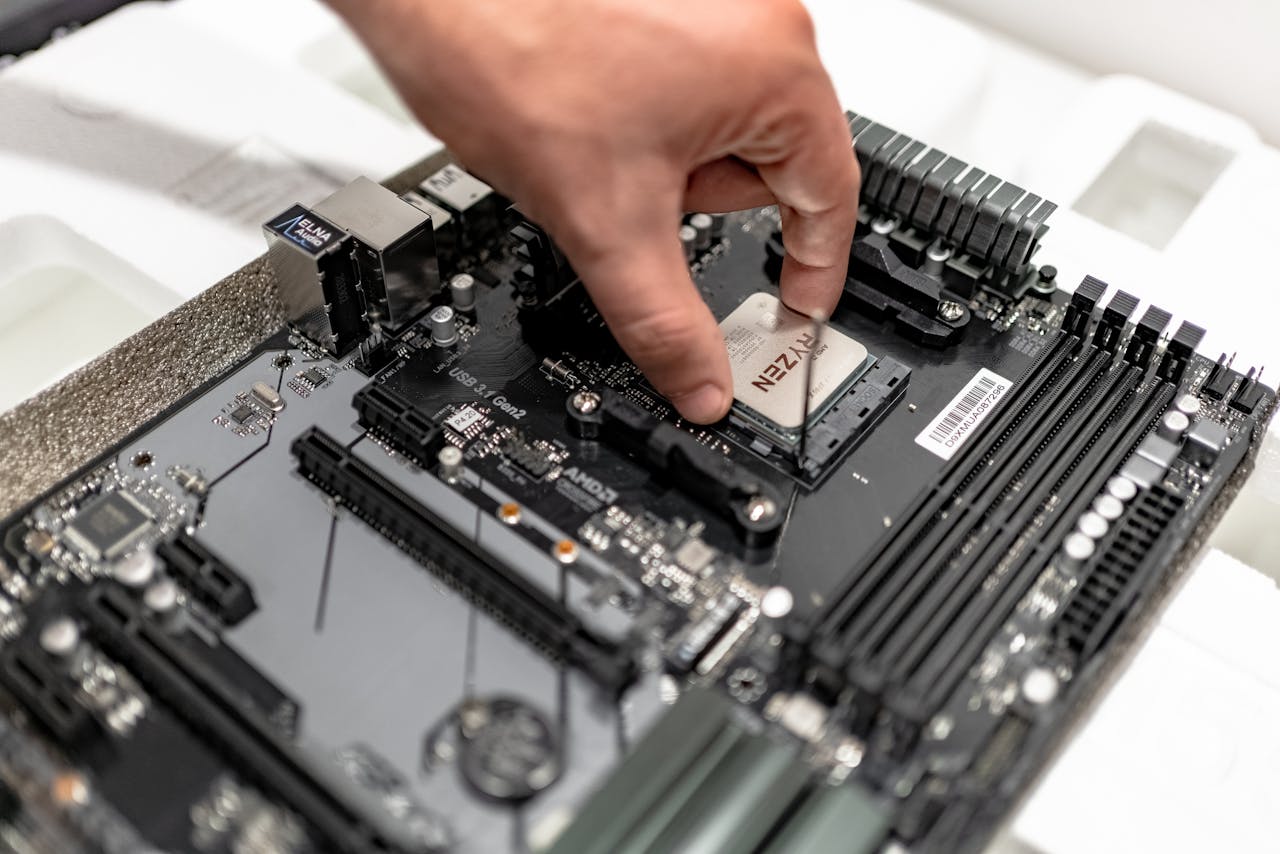 Person's hand installing a CPU on a motherboard, showcasing PC maintenance and repair.